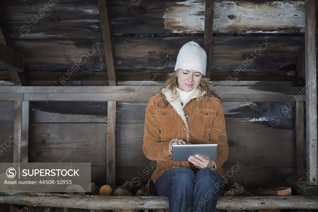 An organic farm in upstate New York, in winter. A woman sitting in an outbuilding using a digital tablet.  West Kill, New York, USA