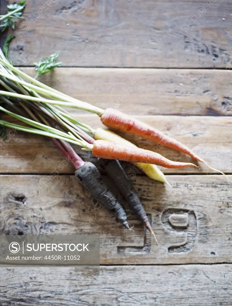 A domestic kitchen table with a worn scrubbed surface. A bunch of fresh carrots.  Provo, Utah, USA