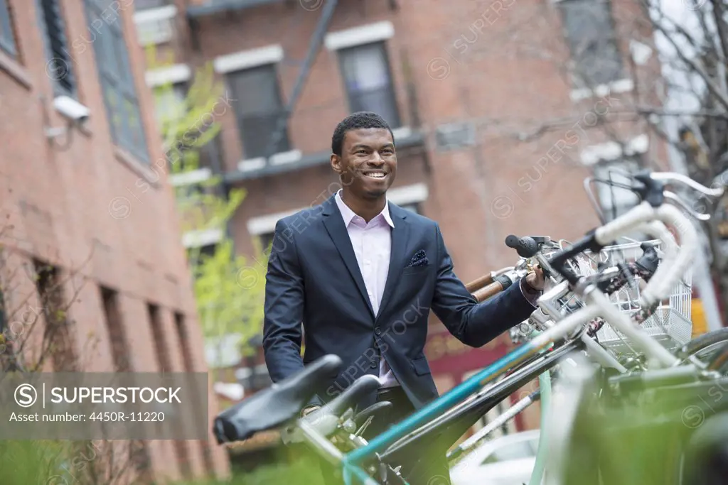 City life in spring. A man in a blue suit, by a bicycle rack in a city park.  New York city, USA