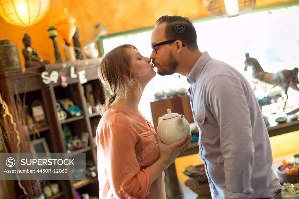 Two people, a couple running an antique store. Small business. Kissing each other.  High Falls, New York, USA