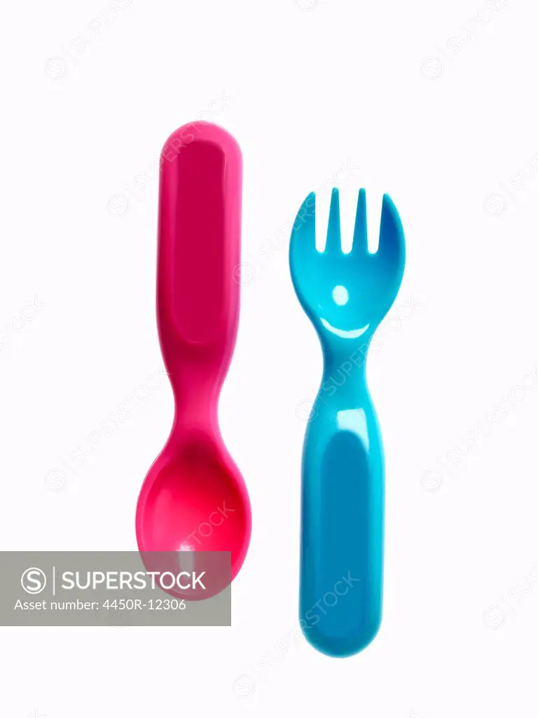 A pink plastic baby spoon and a blue fork.  New York City, USA