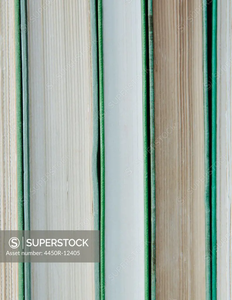 Books in a row, with green hard covers, and white and beige paper edges.