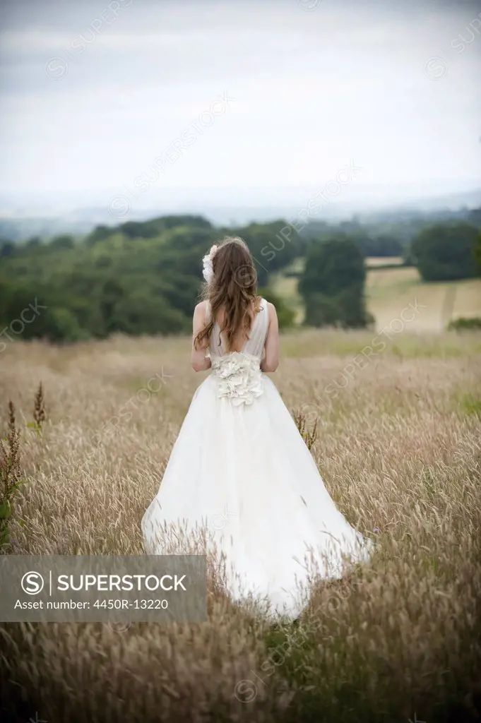 A bride in her wedding dress standing in a field. England. 07/04/2010
