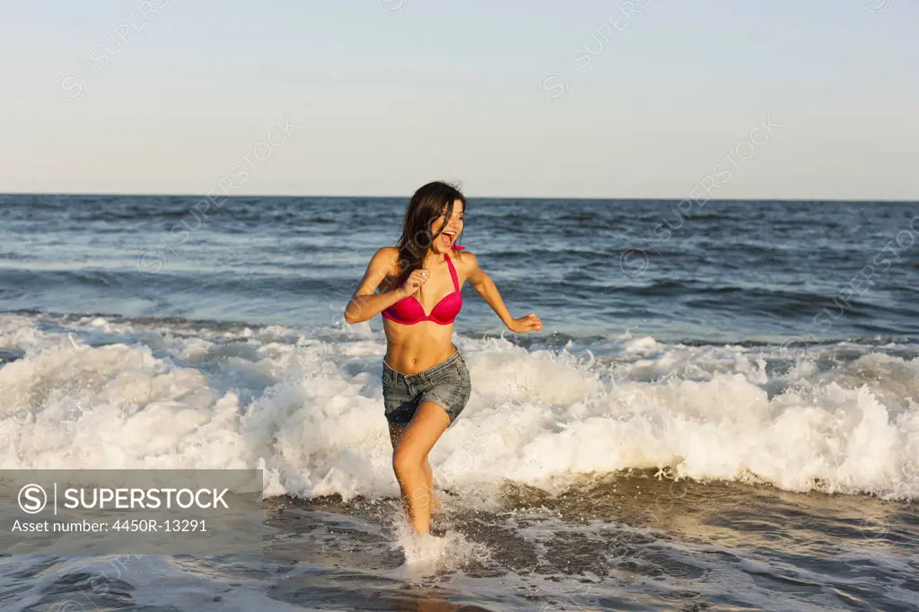 A beautiful young women at the water's edge on the beach in Atlantic City. New Jersey, USA. 01/08/2012