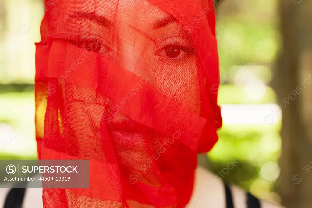 A young woman with a red see-through sheer veil across her face. Pennsylvania, USA. 05/02/20132