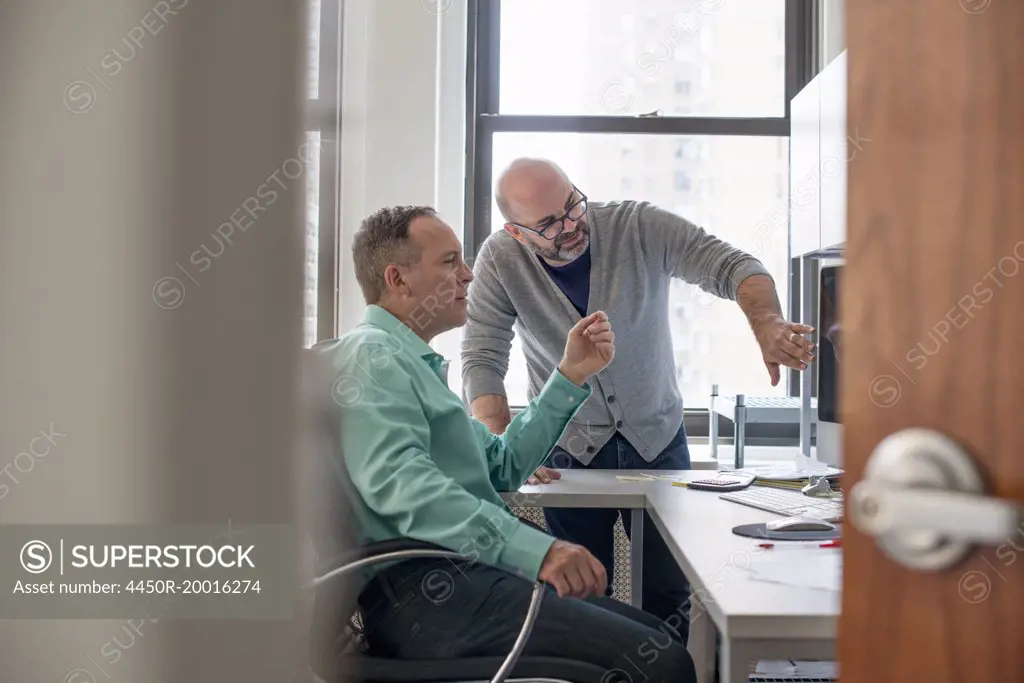 Two men in an office looking at a computer screen.
