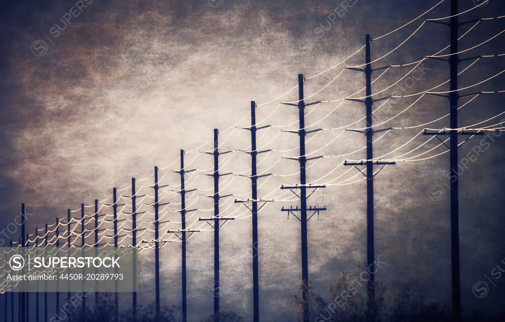 Power lines at regular intervals reaching into the distance against a patch of clearing sky and cloud.