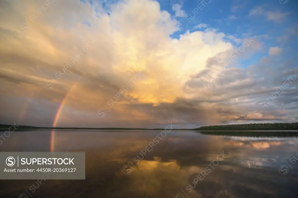 A rainbow and a dramatic cloud formation over a lake.