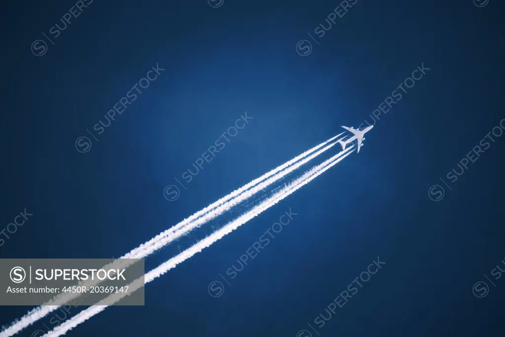 A jet vapour trail across a dark blue sky.