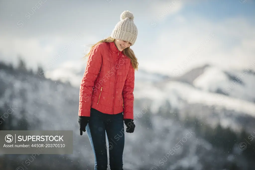 A young girl in a red coat and woolly hat outdoors in the winter.