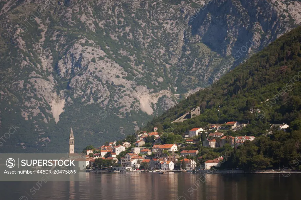 View across a lake towards a village on the slopes of a mountain in Montenegro.