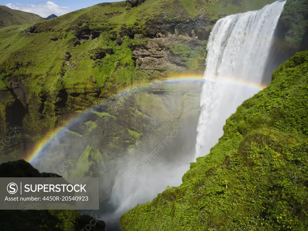 Skogafoss waterfall, a cascade over a sheer cliff, and a rainbow in the mist.