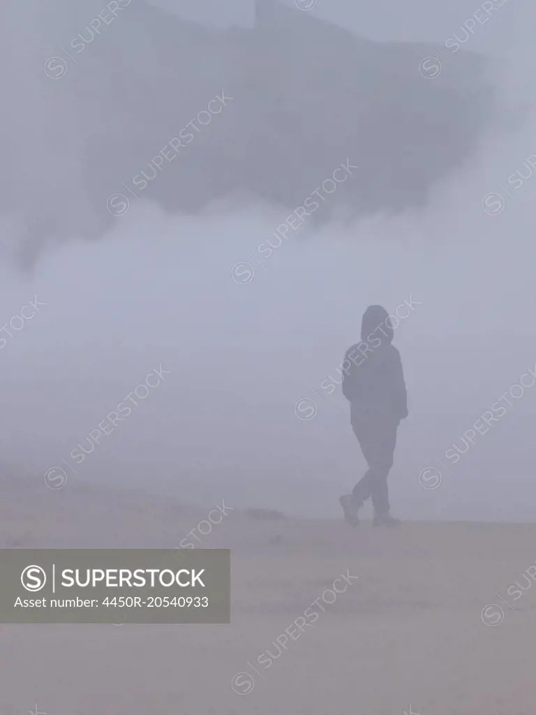 A person walking through the vapour and steam from the hot springs.