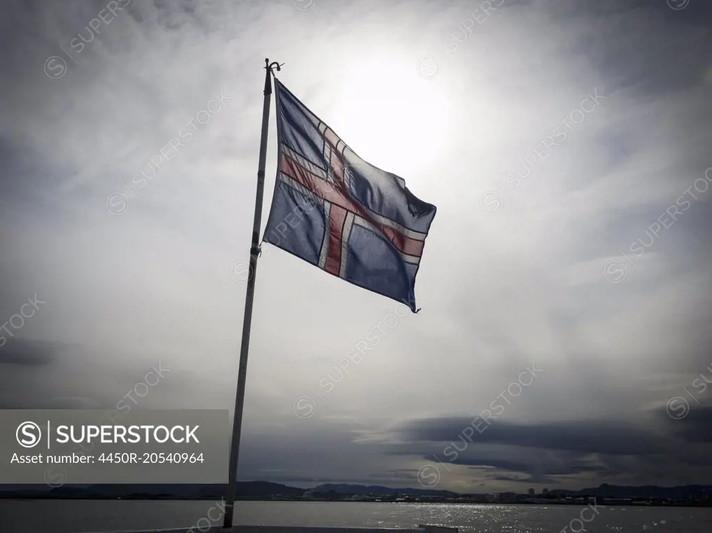 The national flag of Iceland, flying against a cloudy sky