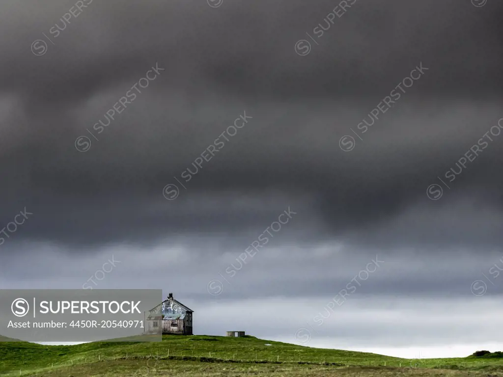 A barn on the crest of a hill, and dark storm clouds glowering over the land.