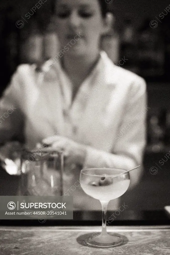A woman mixing a cocktail, a mixologist at work.
