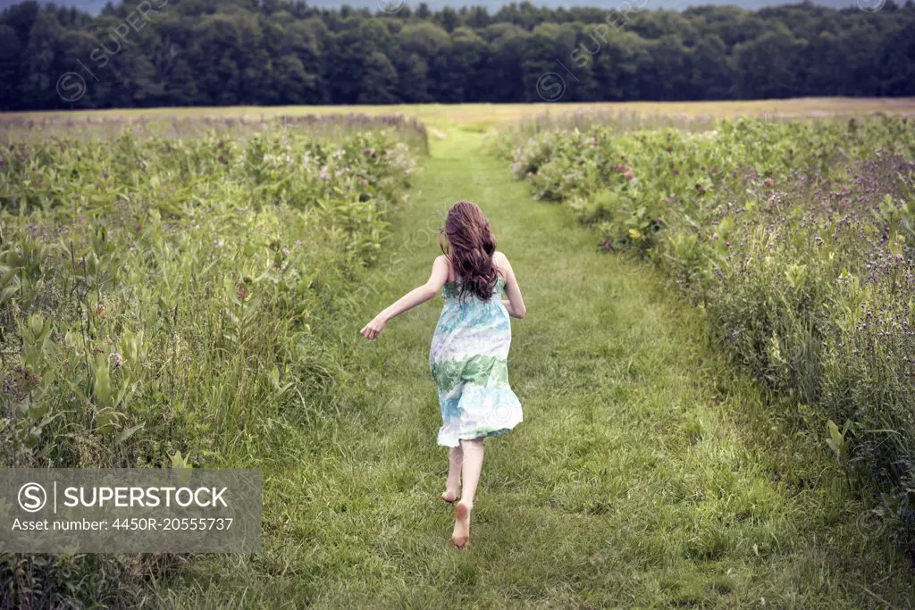 A girl running through a meadow in summer.