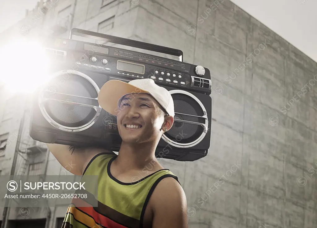 A young person with a boombox on the street of a city.
