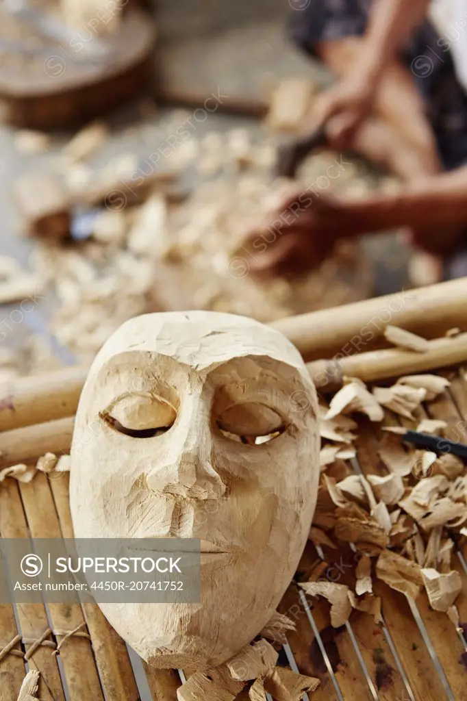 A traditional wooden mask being made in a carver's workshop.