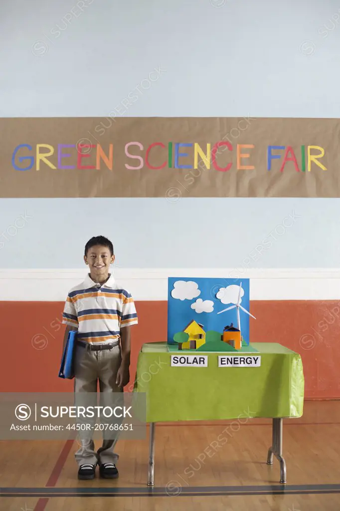 A boy standing under a Green Science Fair sign beside a Solar Power presentation.