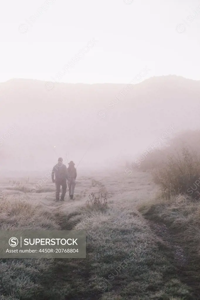 Two people, a man and woman walking along a path on a frosty morning.