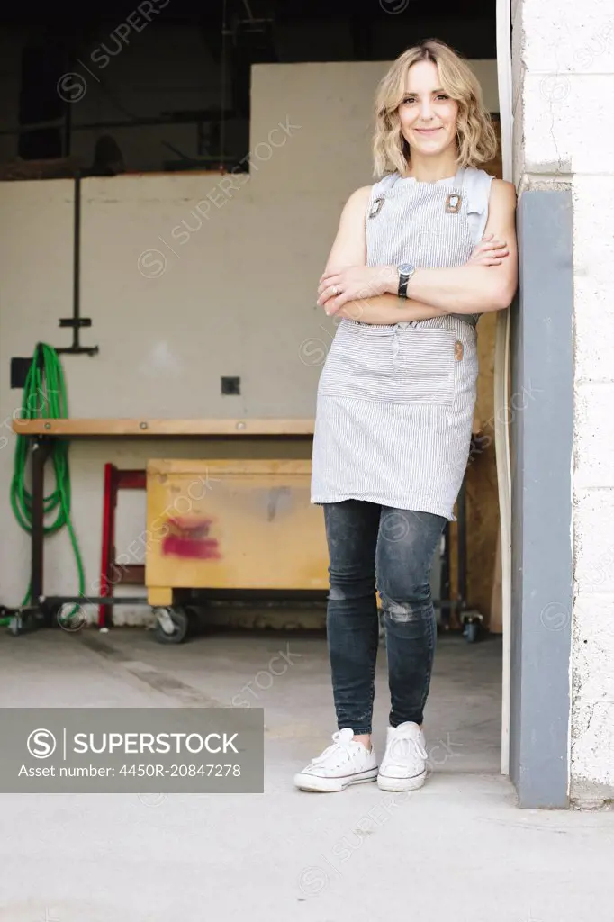 A business owner and craftsman standing in the doorway of her workshop.