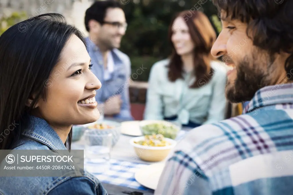 Friends around a table, men and women laughing and talking.