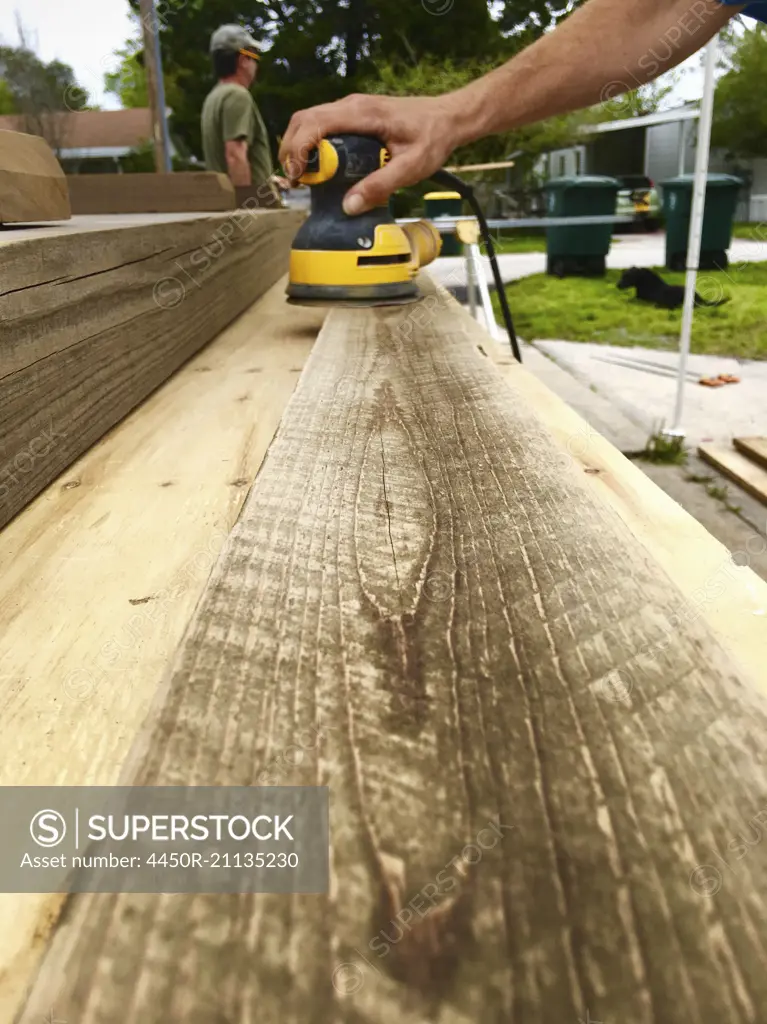 Close up of a man planing a plank of wood.