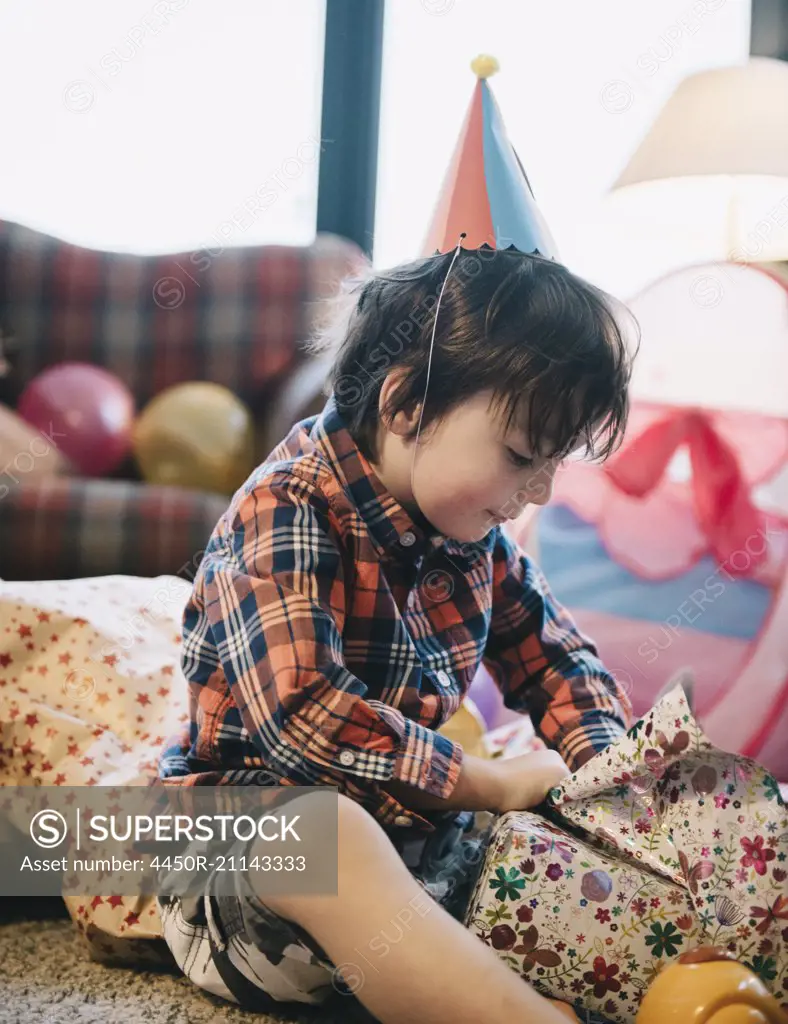 A boy unwrapping his presents at his birthday party.