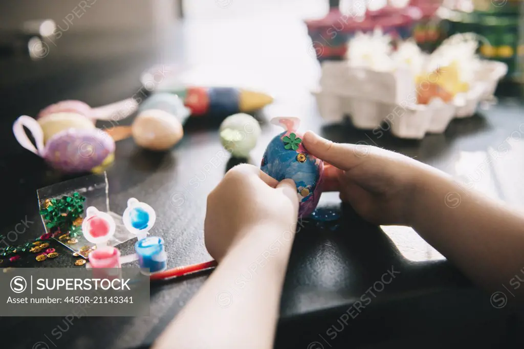 A child decorating eggs at Easter with glitter, glue and paint.