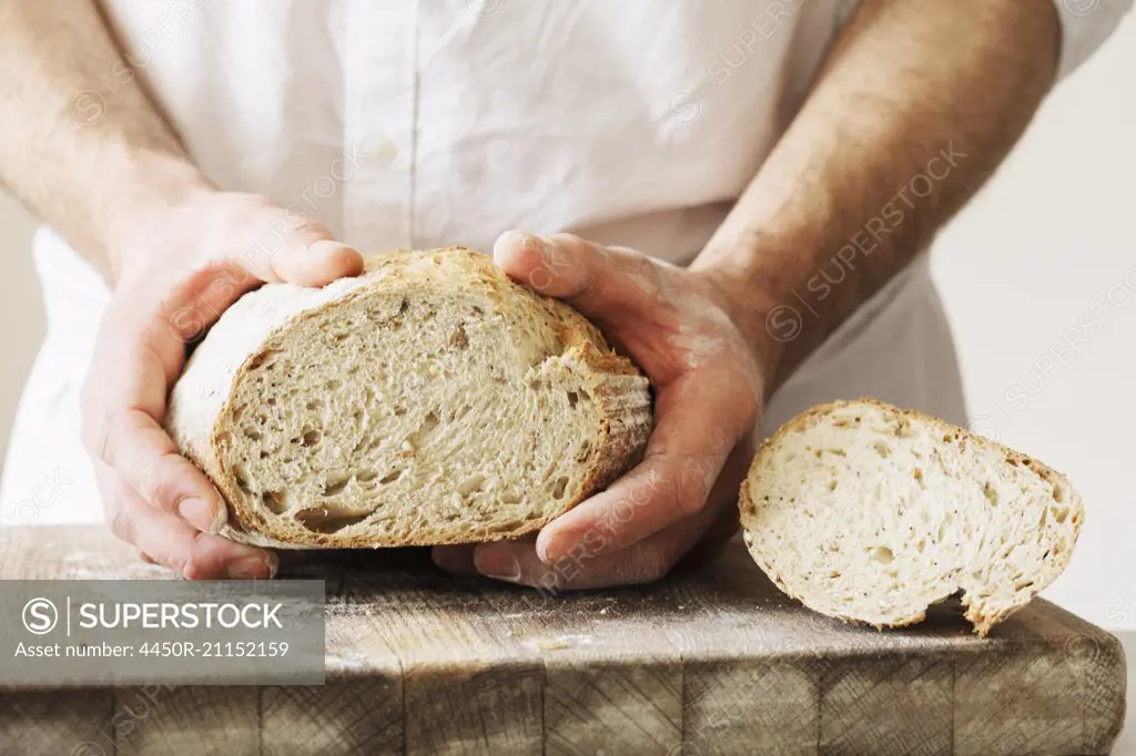 Baker holding a freshly baked loaf of bread.