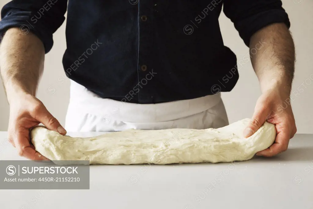 Close up of a baker kneading bread dough.