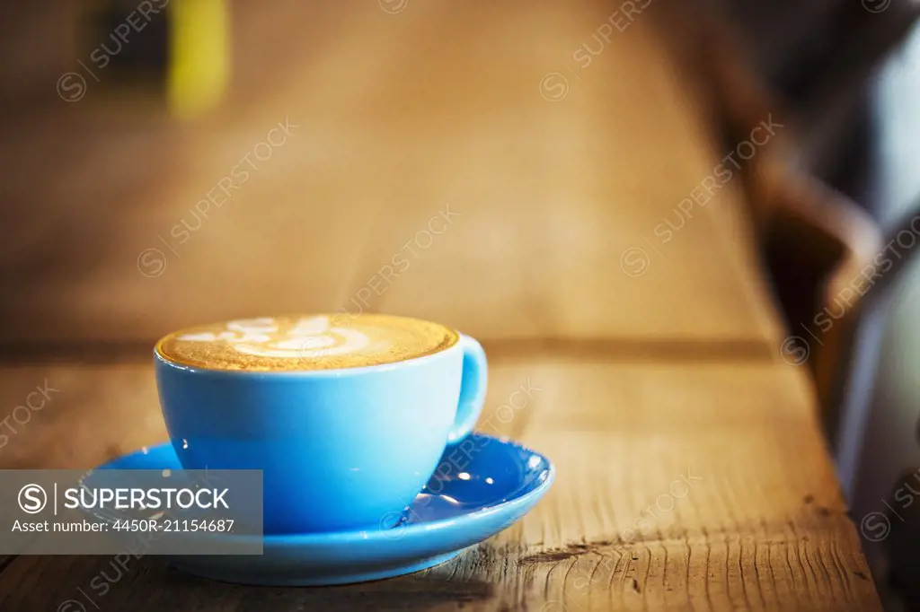 Specialist coffee shop. A blue china cup and saucer wth frothy coffee.