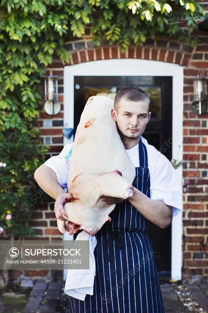 The Red Lion village public house chef carrying a large carcass of an animal, meat for the restaurant.