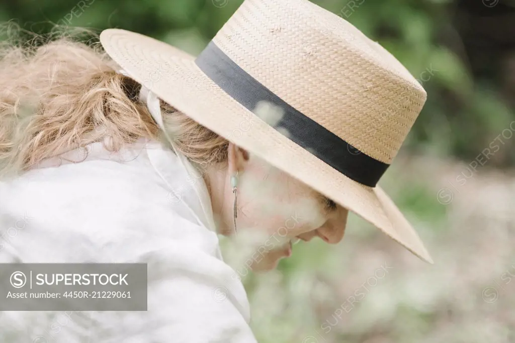 A woman in a wide brimmed straw hat working in a garden.