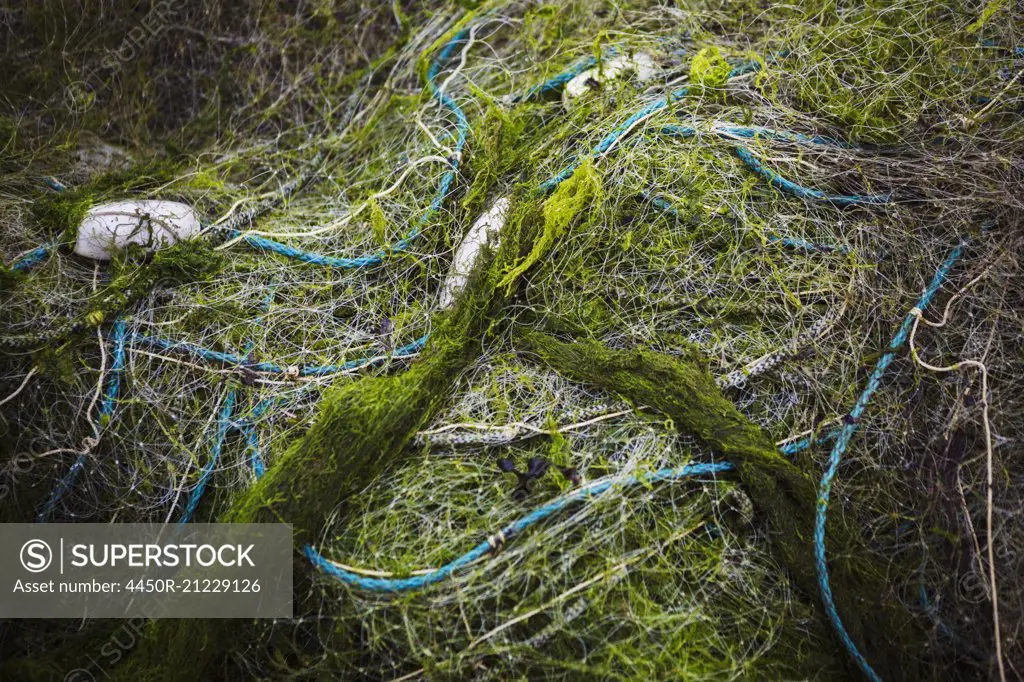 Heaped up fishing nets with floats. - SuperStock
