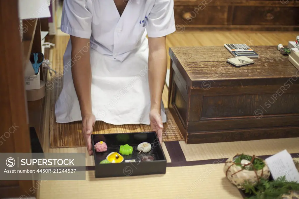 A small artisan producer of specialist treats, sweets called wagashi. A chef presenting a tray of selected wagashi of different shapes and flavours.