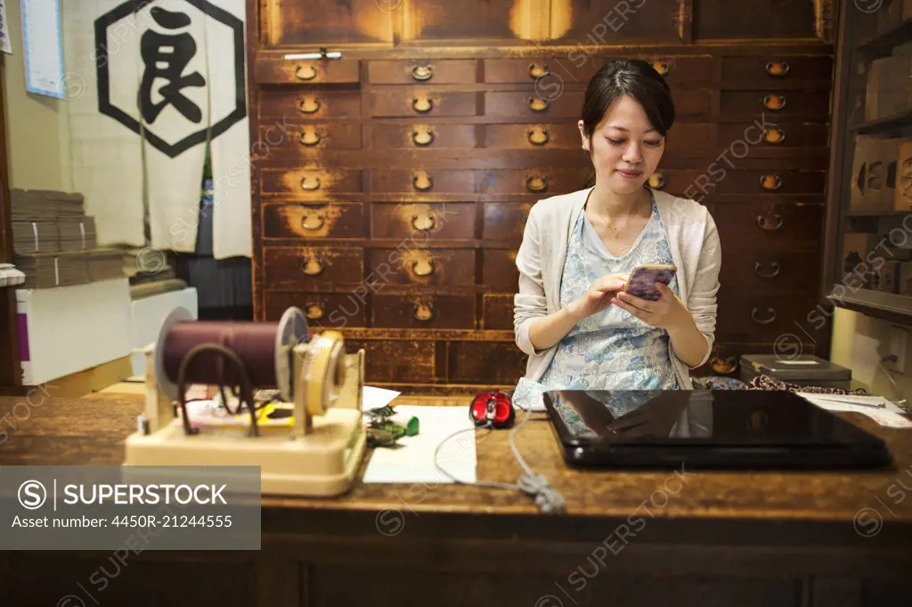 A traditional wagashi sweet shop. A woman working at a desk using a laptop and phone.