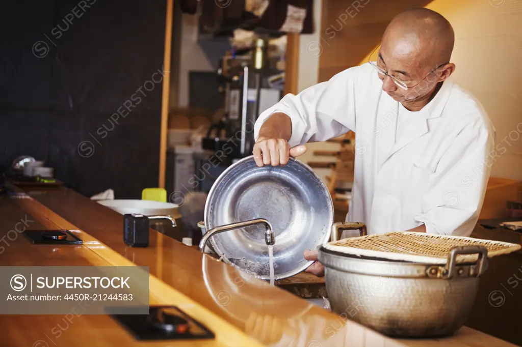 A chef working in a small commercial kitchen, an itamae or m,aster chef making sushi.