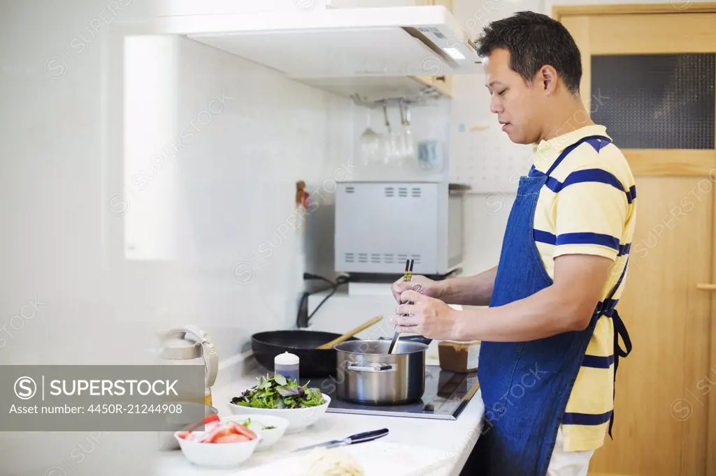 Family home. A man in a blue apron preparing a meal.
