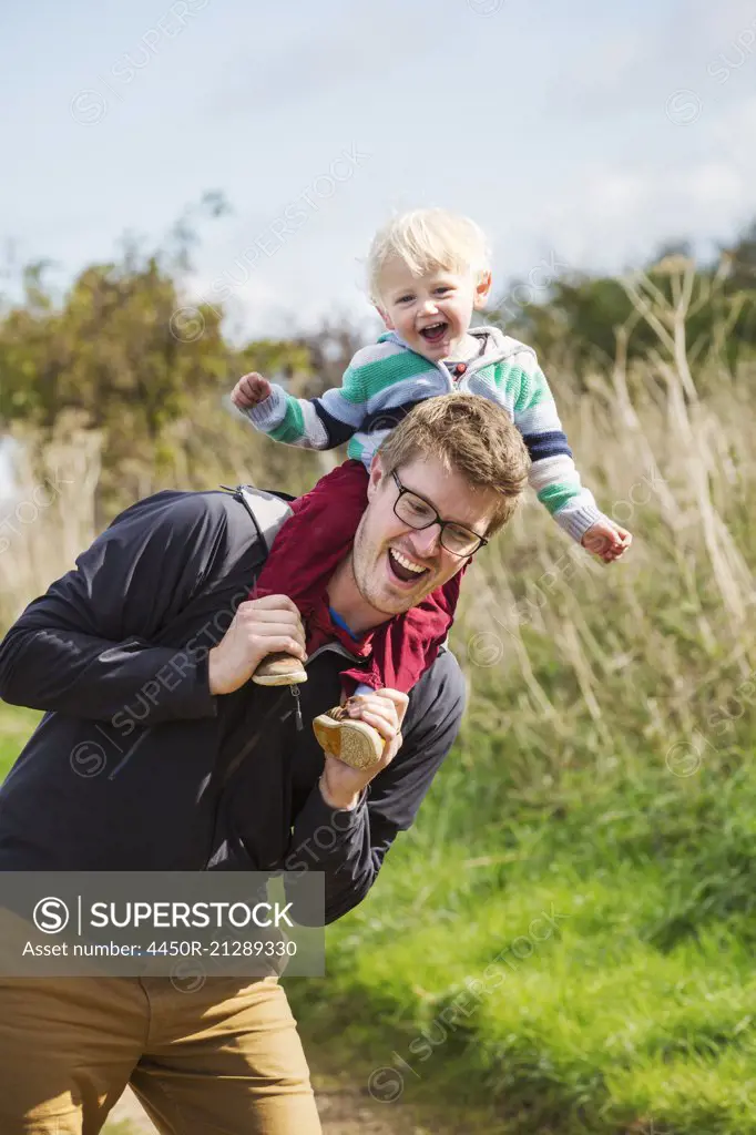 A man and a small boy on a walk, a father giving his son a piggyback.