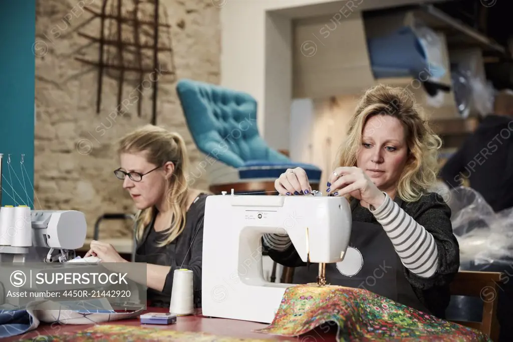 An upholstery workshop. Two women seated using sewing machines.