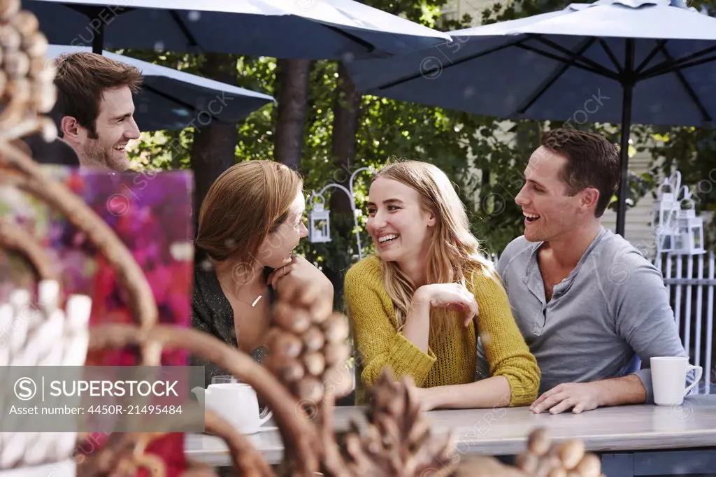 A group of people sitting at a long table in an outdoor cafe.