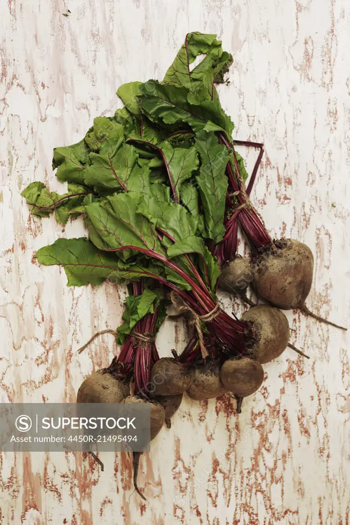 A shot of bundles of beets on a wooden surface, seen from above.