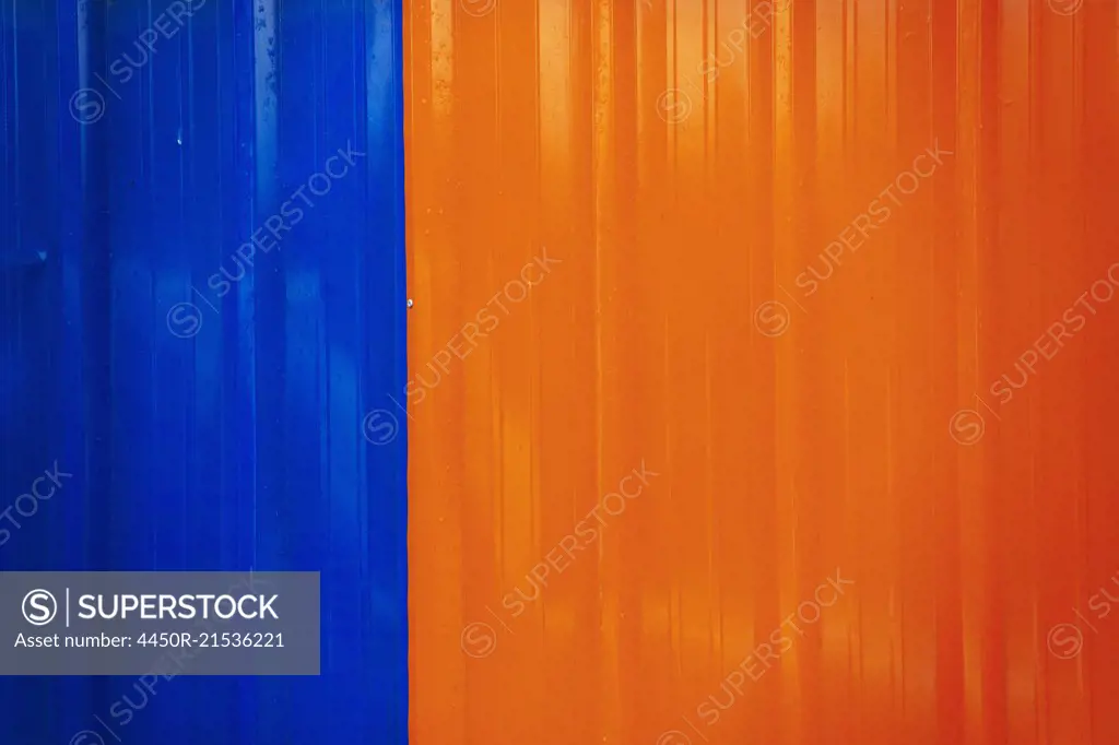 A shiny painted surface on a wall, coloured orange and blue.