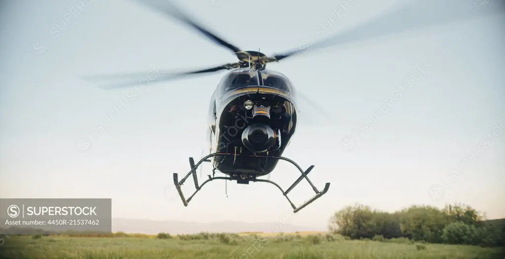A helicopter landing or taking off in a rural landscape.