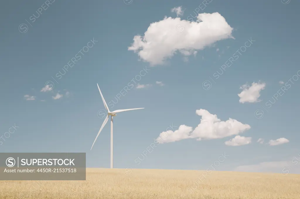 A wind turbine in a desert landscape against blue sky.