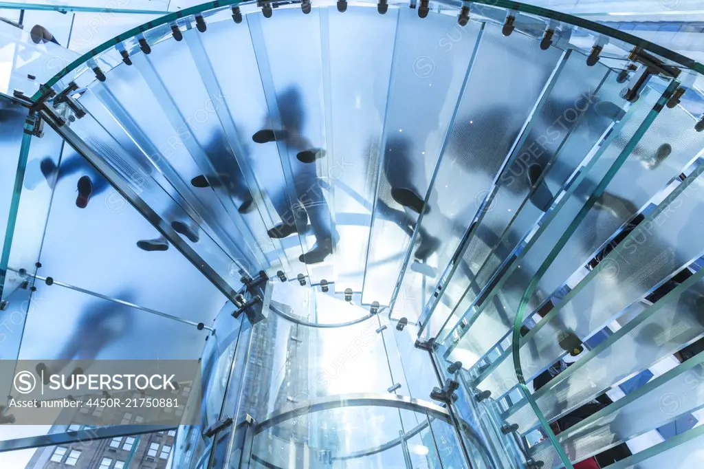 Low angle view of people walking on transparent spiral staircase.