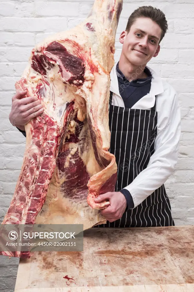 A butcher holding a carcass of spring lamb butchered and halved.