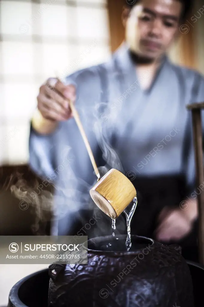 Close up of traditional Japanese Tea Ceremony, man using a Hishaku, a bamboo ladle, to pour hot water.